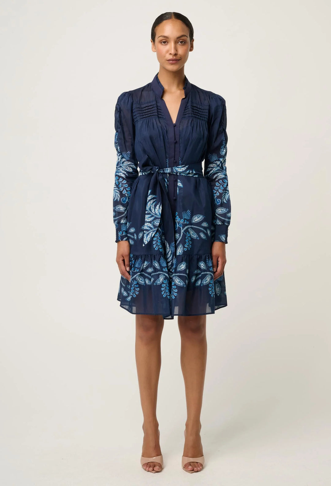 Woman wearing a navy blue dress with floral pattern on a white background