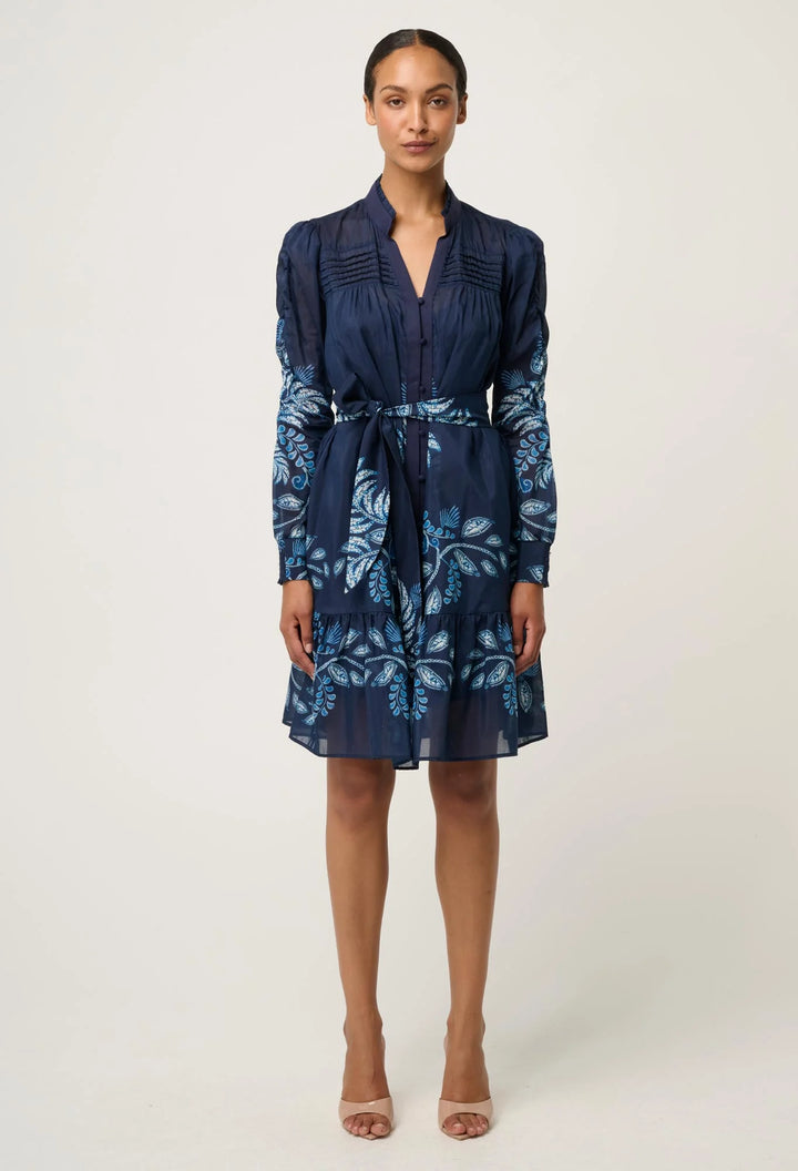 Woman wearing a navy blue dress with floral pattern on a white background