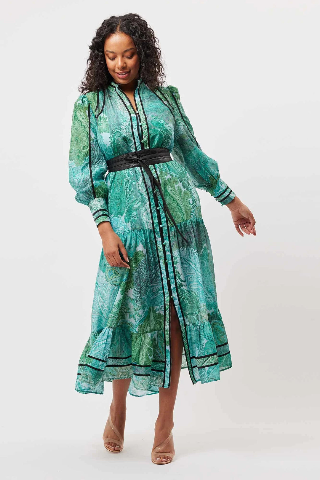 Woman wearing a green patterned dress with a belt on a white background