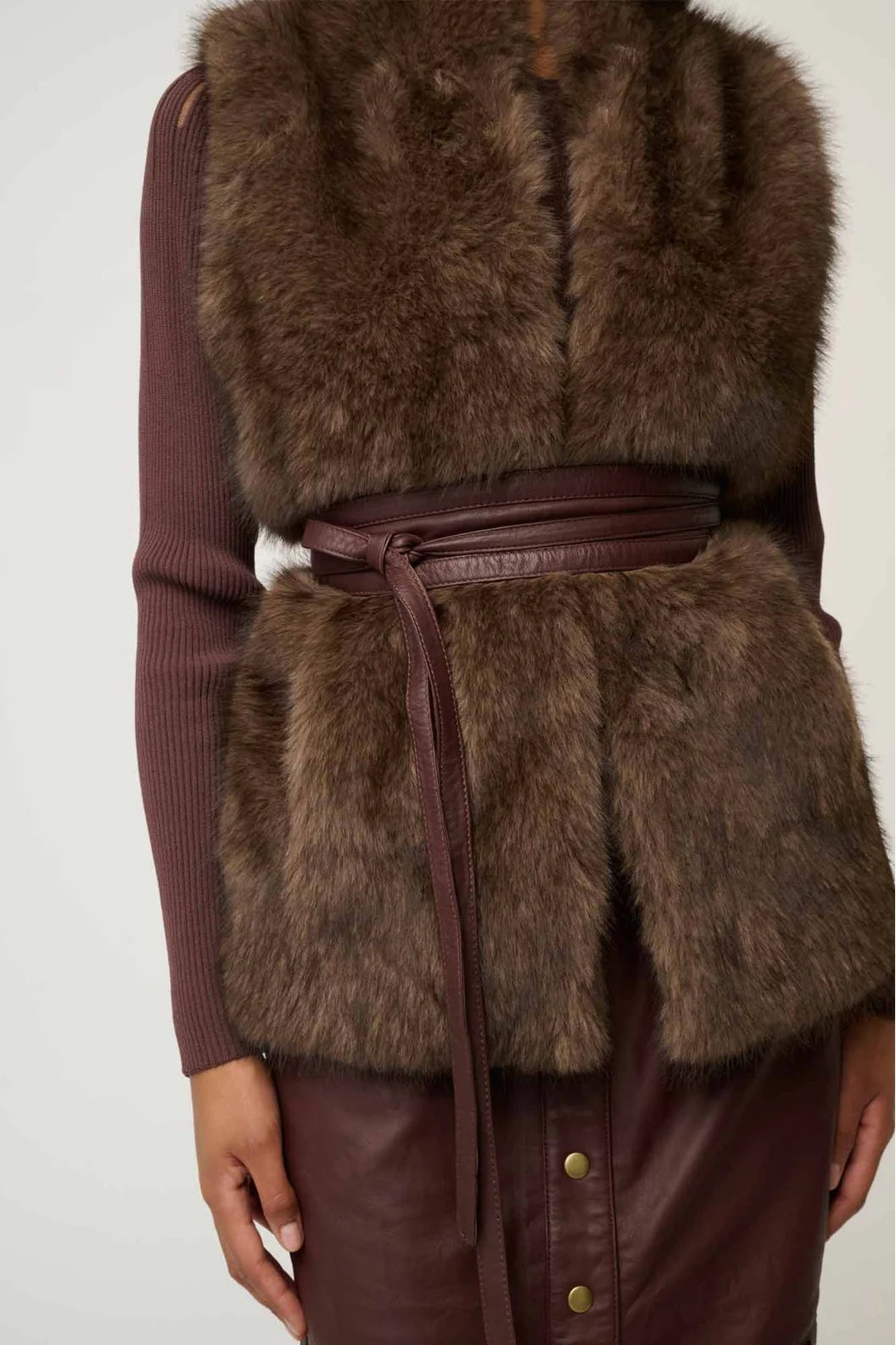 Brown fur vest with leather accents on a plain background