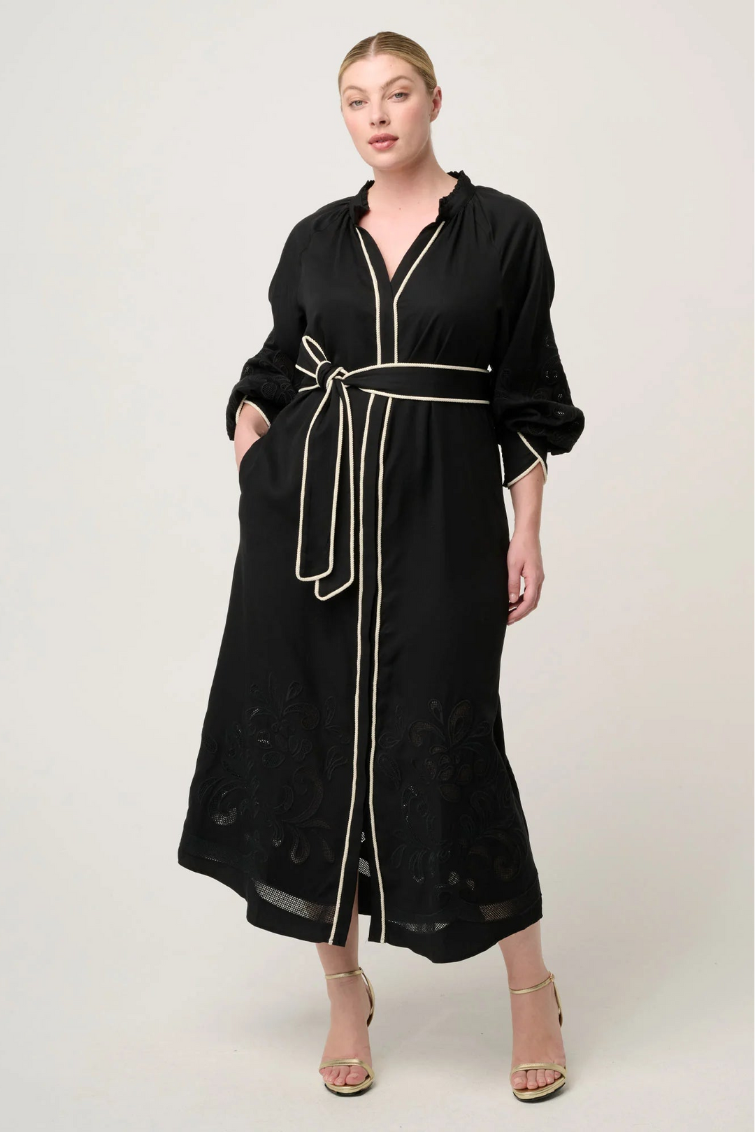 Woman wearing a black dress with white trim on a white background