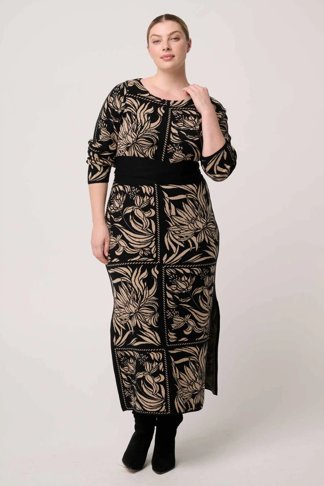 Woman wearing a long, patterned dress against a white background