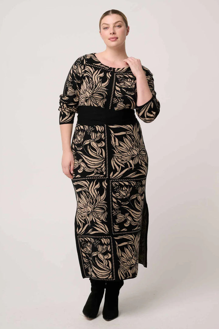 Woman wearing a long, patterned dress against a white background