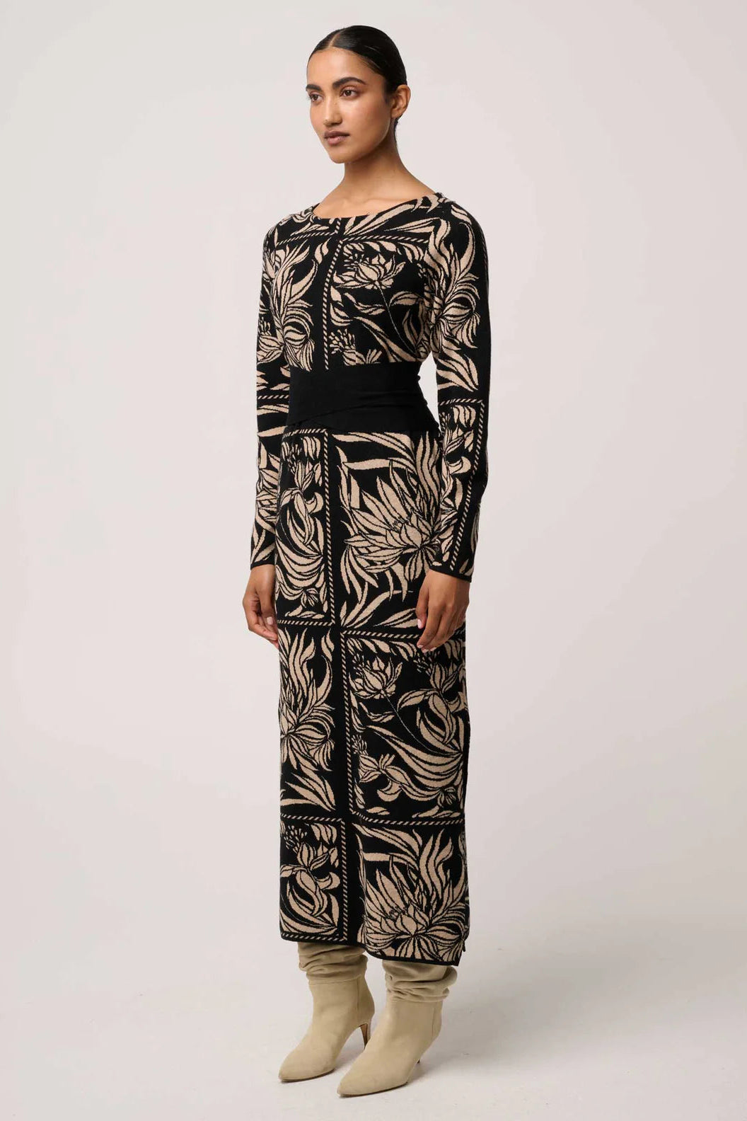 Woman wearing a black and beige patterned outfit on a white background