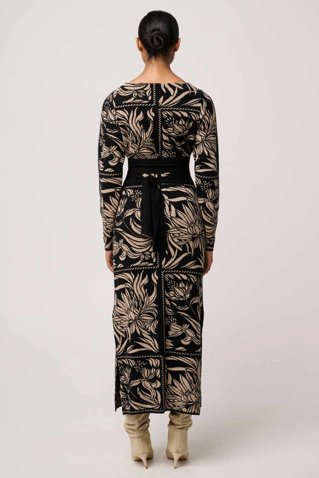 Person wearing a long, patterned dress with a belt on a white background