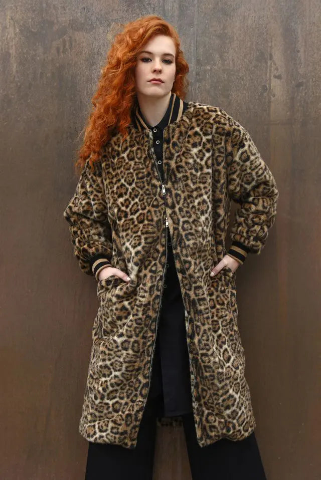 Person wearing a leopard print coat against a brown background