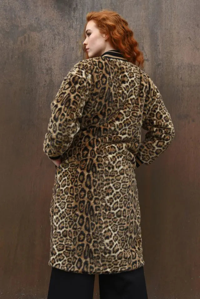 Person wearing a leopard print coat against a textured brown wall