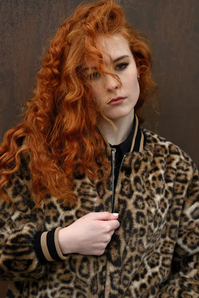Person wearing a leopard print jacket against a brown background
