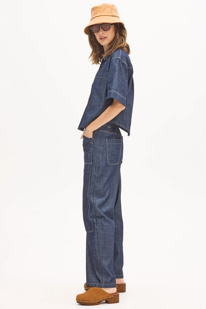 Person wearing a denim outfit with a beige hat on a white background