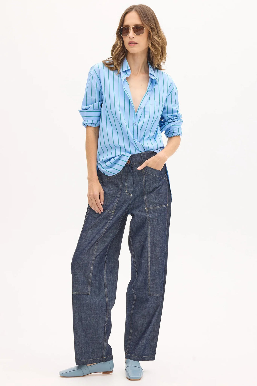 Woman wearing a blue striped shirt and jeans on a white background