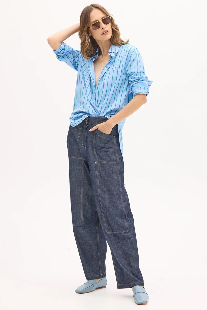 Woman wearing a blue striped shirt and denim pants on a white background