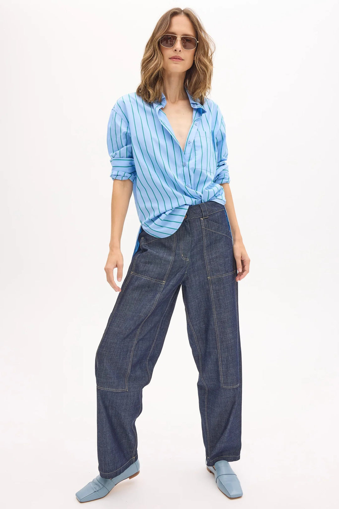 Woman wearing a blue striped shirt and denim pants on a white background
