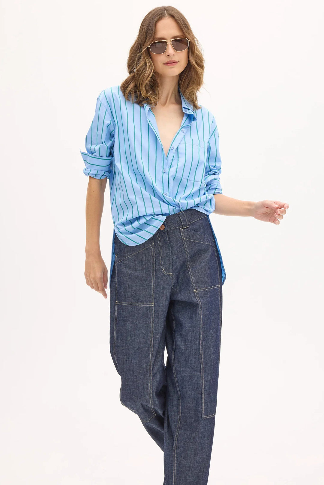 Woman wearing a blue striped shirt and denim pants on a white background