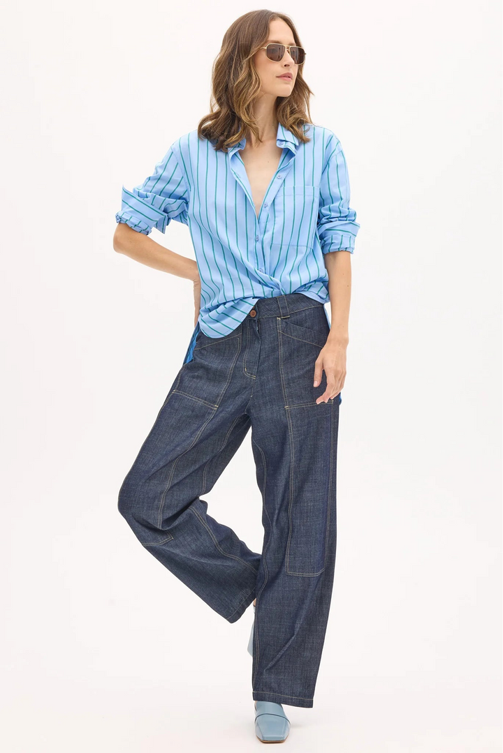 Woman wearing a blue striped shirt and dark jeans on a white background
