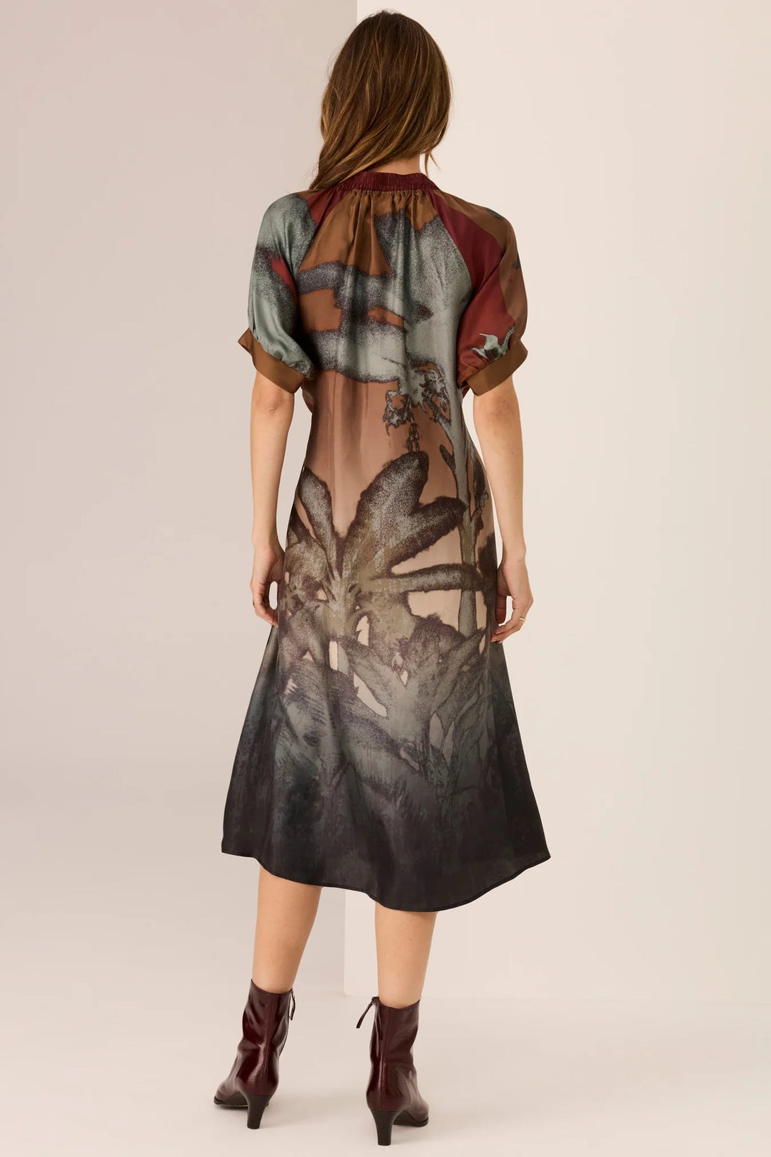 Woman wearing a floral dress with sheer overlay on a beige background
