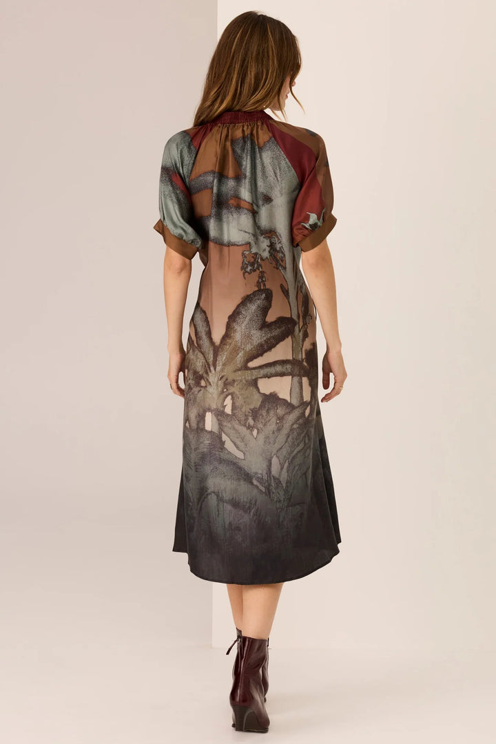 Woman wearing a floral dress with sheer sleeves on a plain background