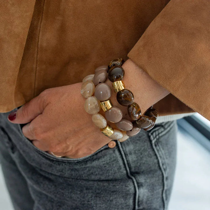 Person wearing a bracelet with brown and beige beads on a blurred background