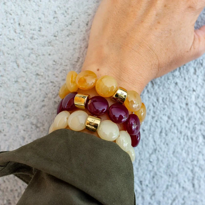 Stack of colorful beaded bracelets on a wrist against a neutral background