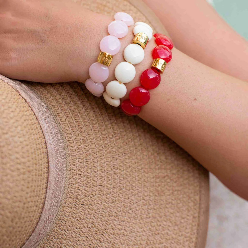 Stack of colorful beaded bracelets on a wrist against a neutral background