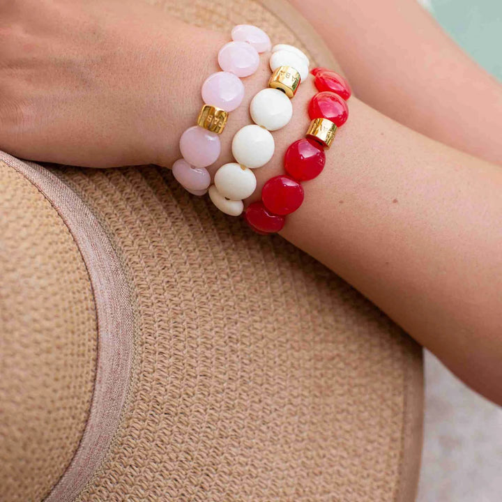 Stack of colorful beaded bracelets on a wrist against a neutral background