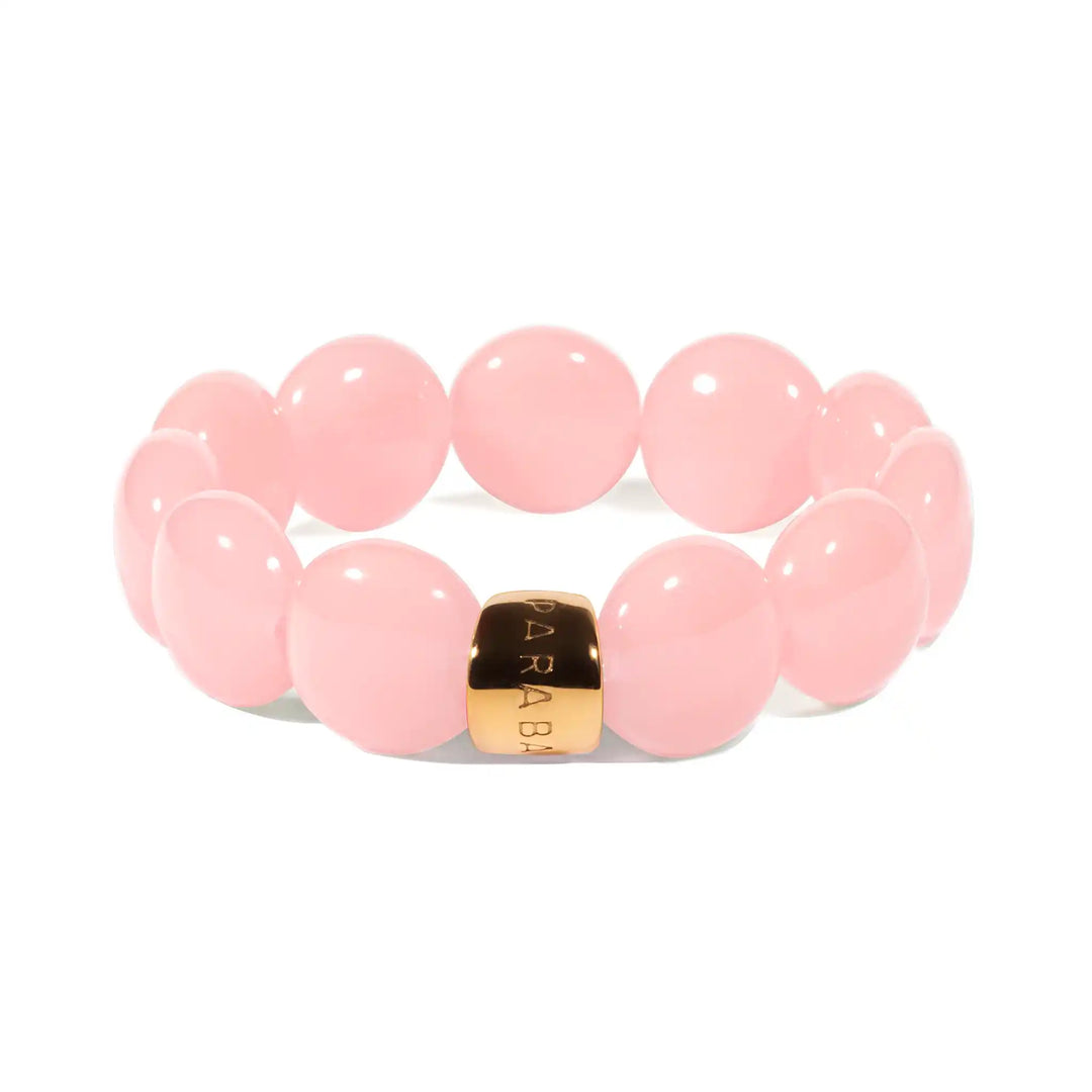 Pink beaded bracelet with a gold accent on a white background