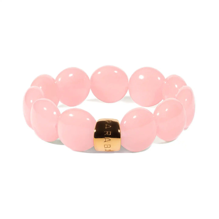 Pink beaded bracelet with a gold accent on a white background