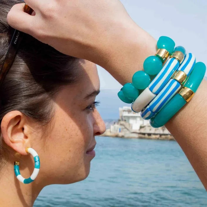 Woman wearing colorful bracelets and earrings by a waterfront