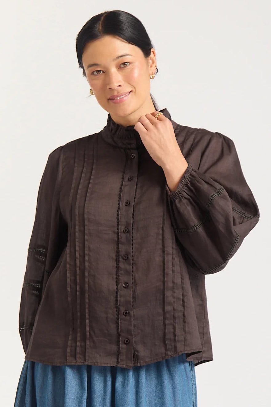 Woman wearing a brown blouse and blue skirt on a white background