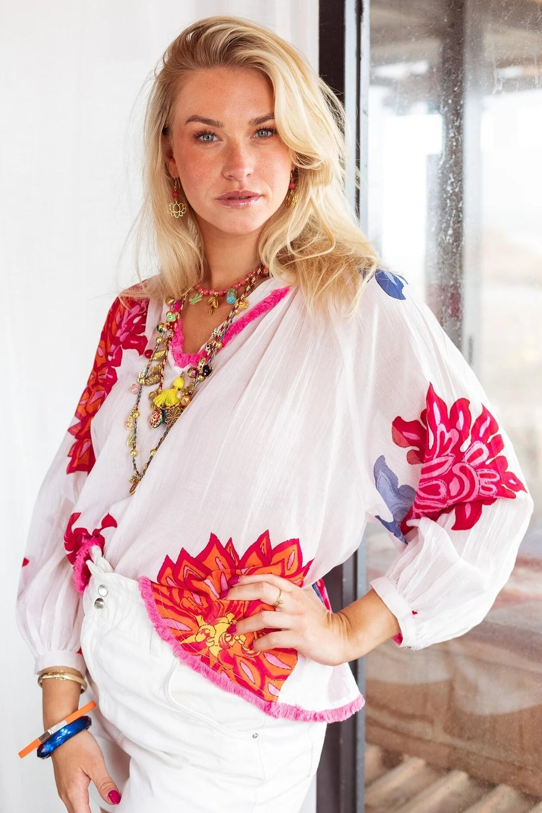 Woman wearing a colorful embroidered blouse with floral patterns indoors.