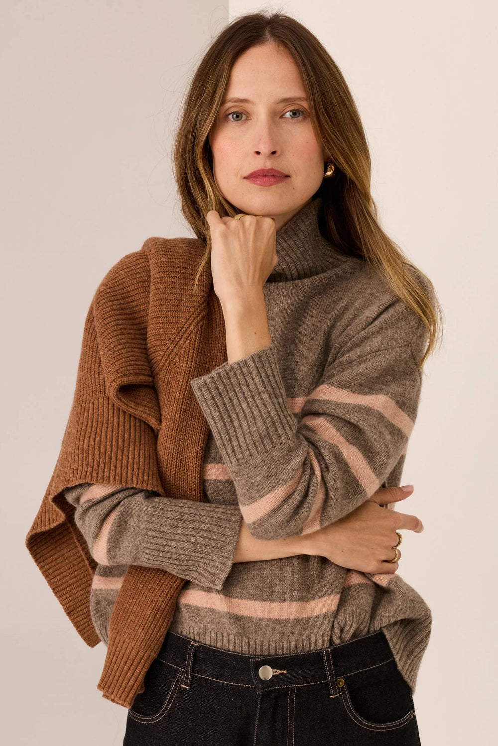 Woman wearing a brown and beige striped sweater with a plain background