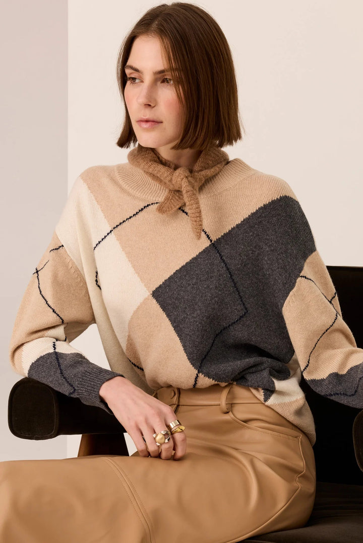 Woman wearing a beige and gray patterned sweater sitting on a chair.