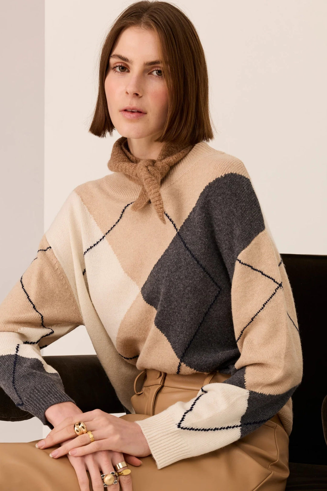 Woman wearing a beige and gray patterned sweater sitting on a couch.