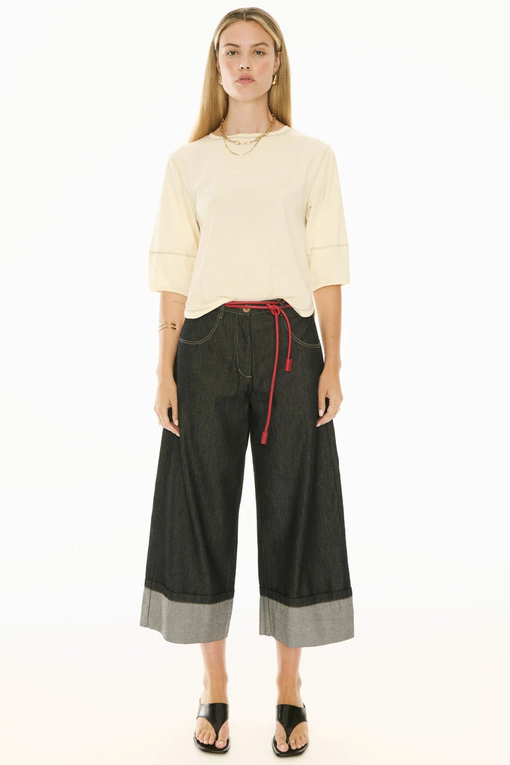 Woman wearing a cream sweater and black wide-leg pants with red drawstring on a white background