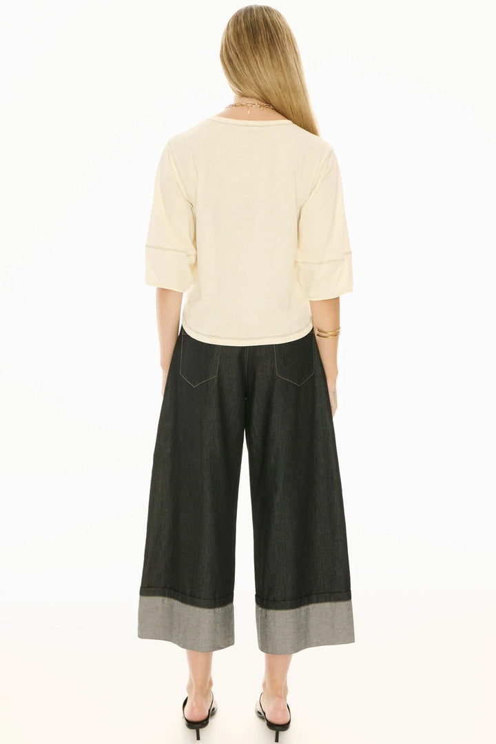 Woman wearing a cream top and black wide-leg pants on a white background