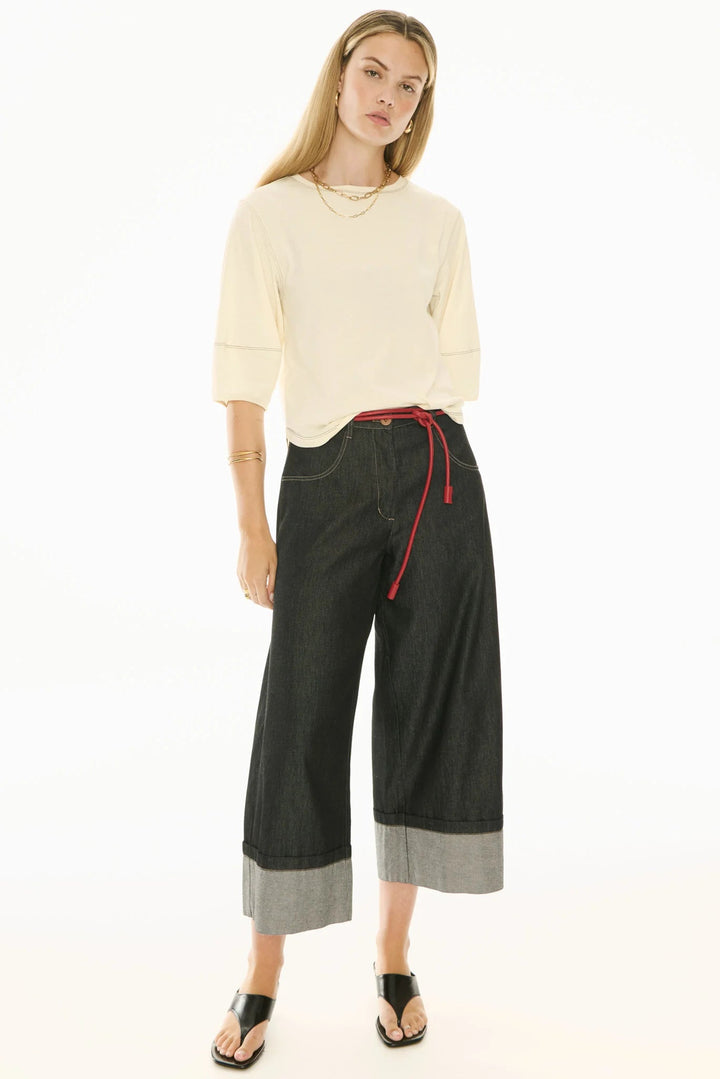 Woman wearing a cream sweater and black wide-leg pants with a red drawstring on a white background