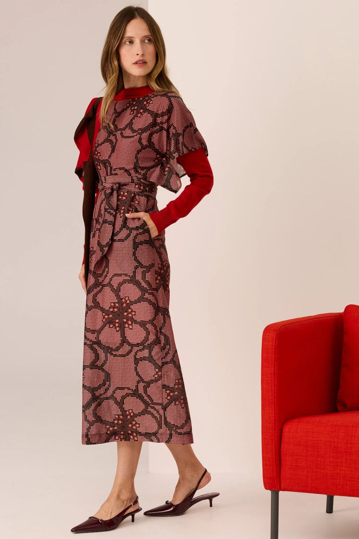 Woman wearing a red floral dress with a red chair in the background