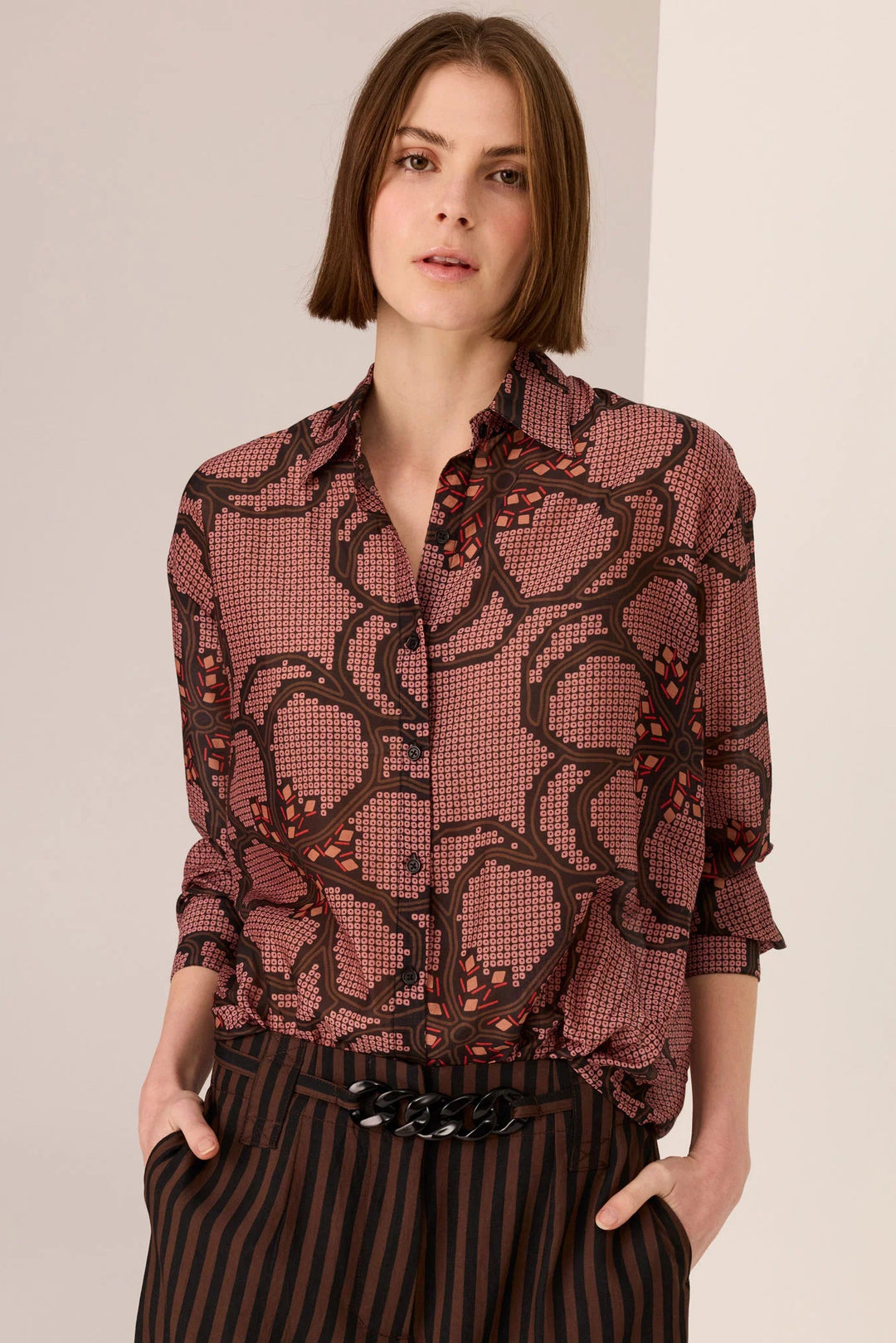 Woman wearing a patterned blouse with a plain background