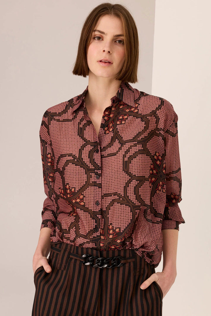 Woman wearing a patterned blouse with a plain background