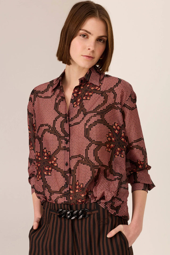 Woman wearing a patterned blouse with a plain background