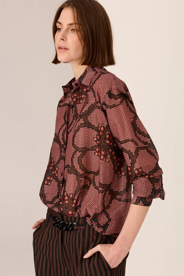 Woman wearing a patterned blouse with a plain background