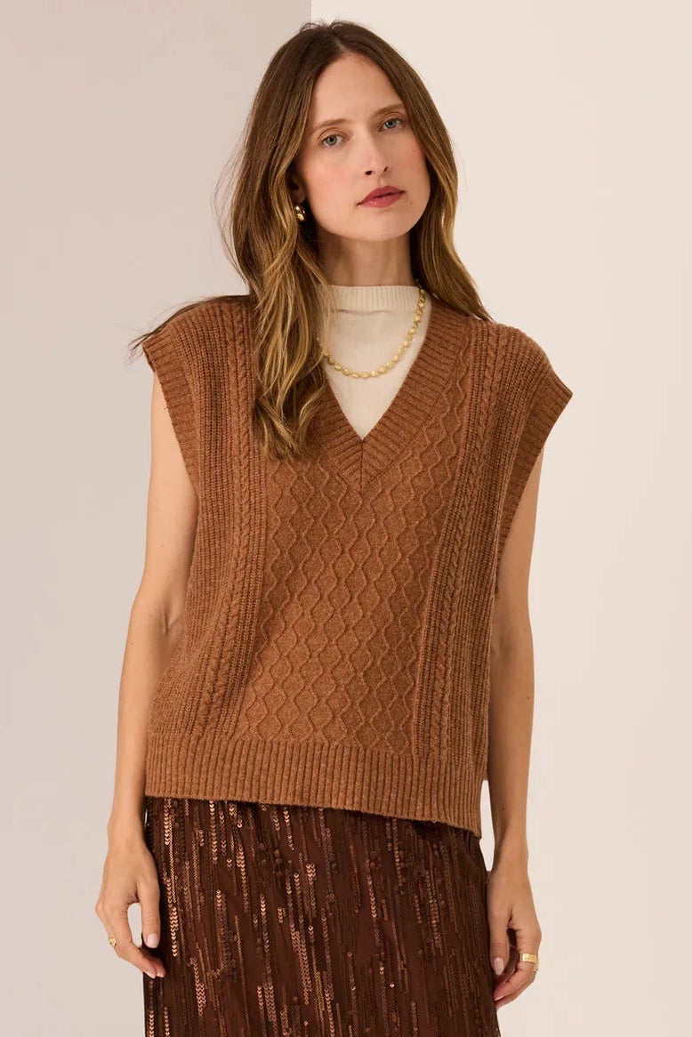 Woman wearing a brown sleeveless top and pleated skirt on a white background