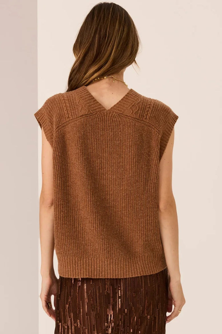 Woman wearing a brown sleeveless top and sequin skirt on a beige background