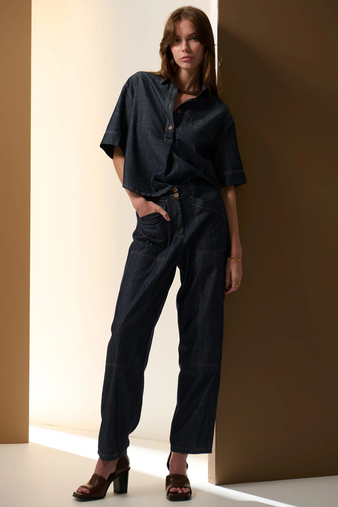 Woman wearing a black outfit against a neutral background. Pol Muhle Denim Top Indigo