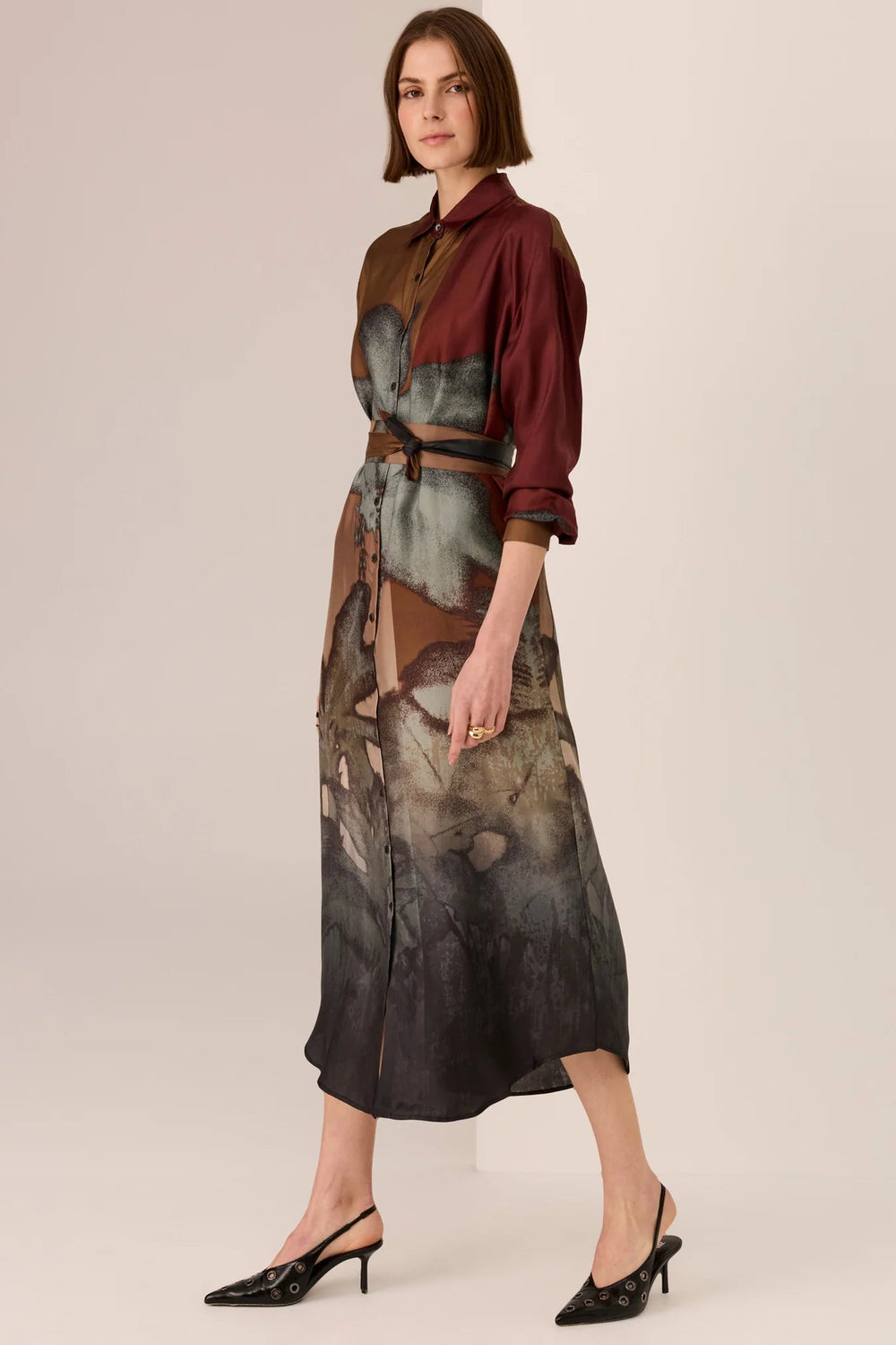 Woman wearing a maroon blouse and patterned skirt on a beige background