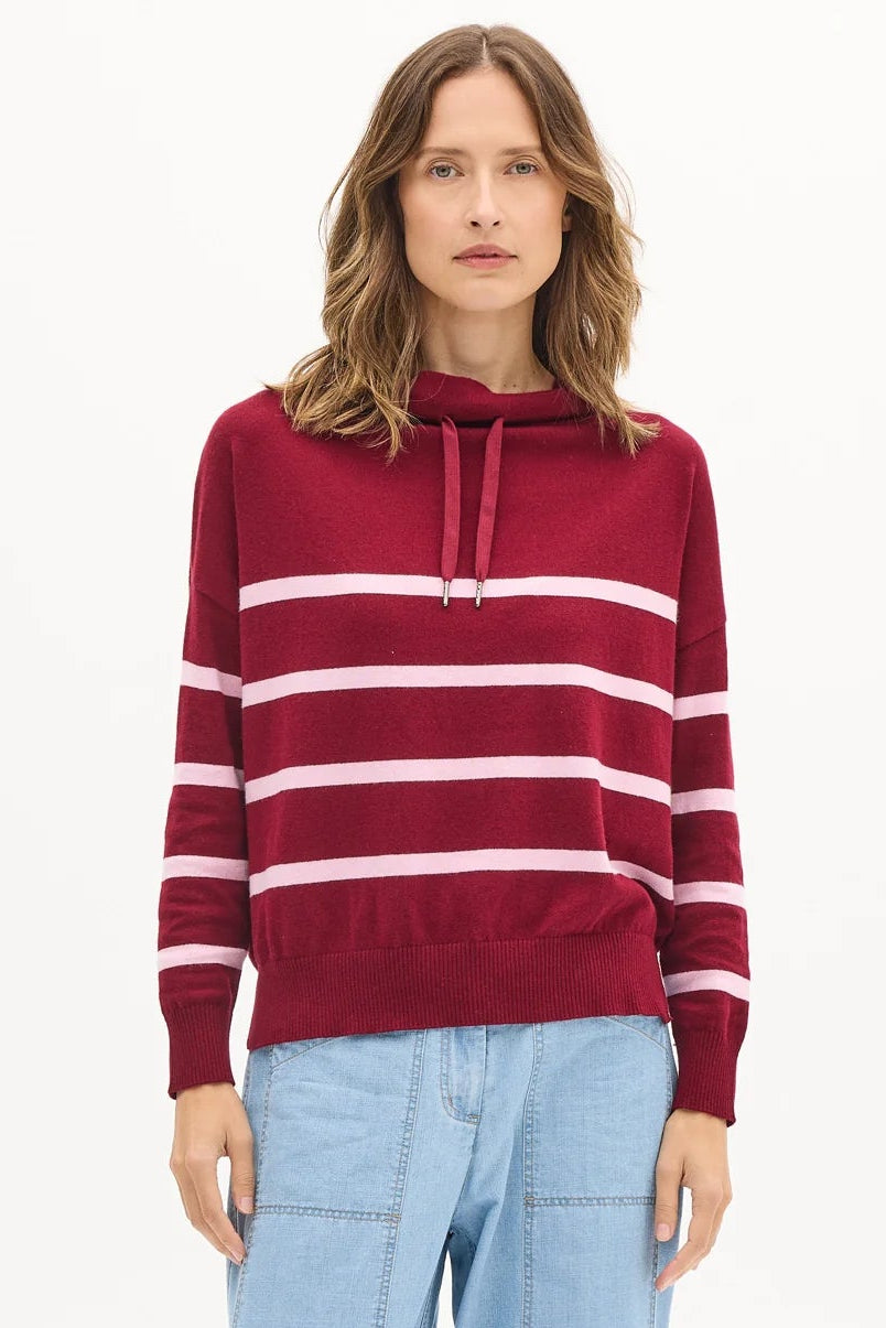 Woman wearing a red and white striped sweater with light blue pants on a white background