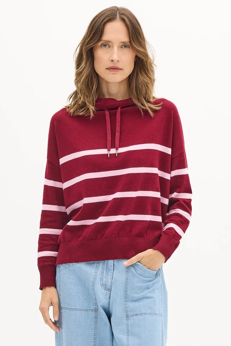 Woman wearing a red and white striped sweater with light blue pants on a white background