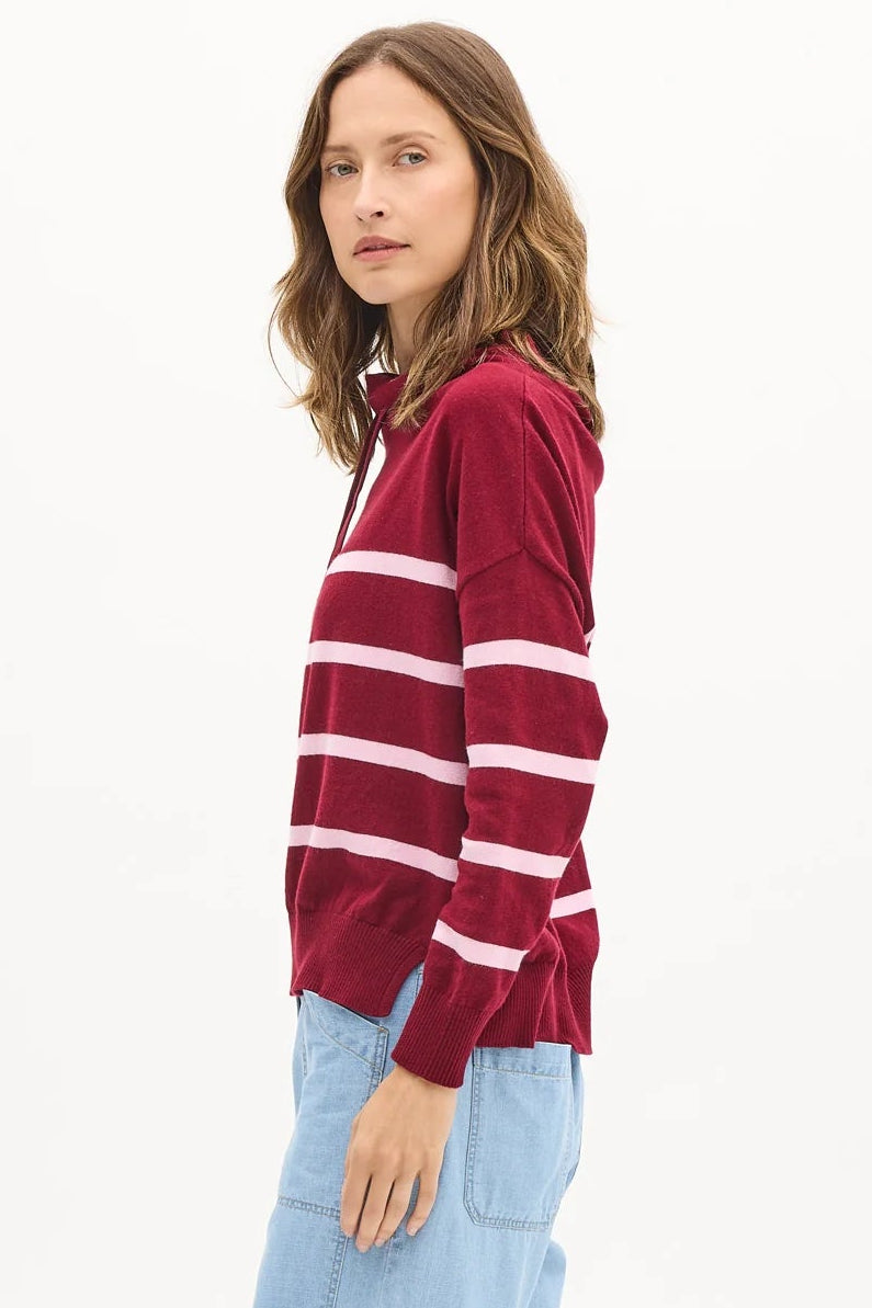 Woman wearing a red and white striped sweater and light blue pants on a white background