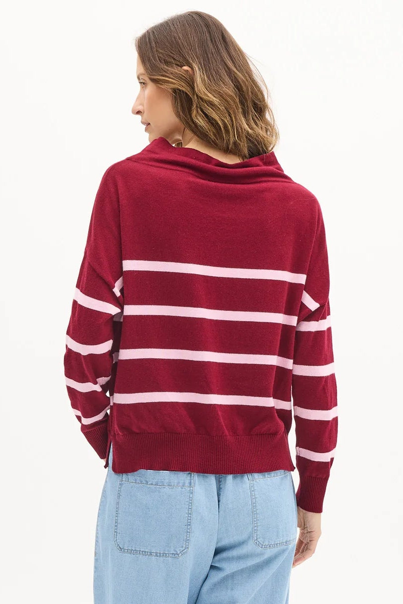 Person wearing a red and white striped sweater with light blue pants on a white background