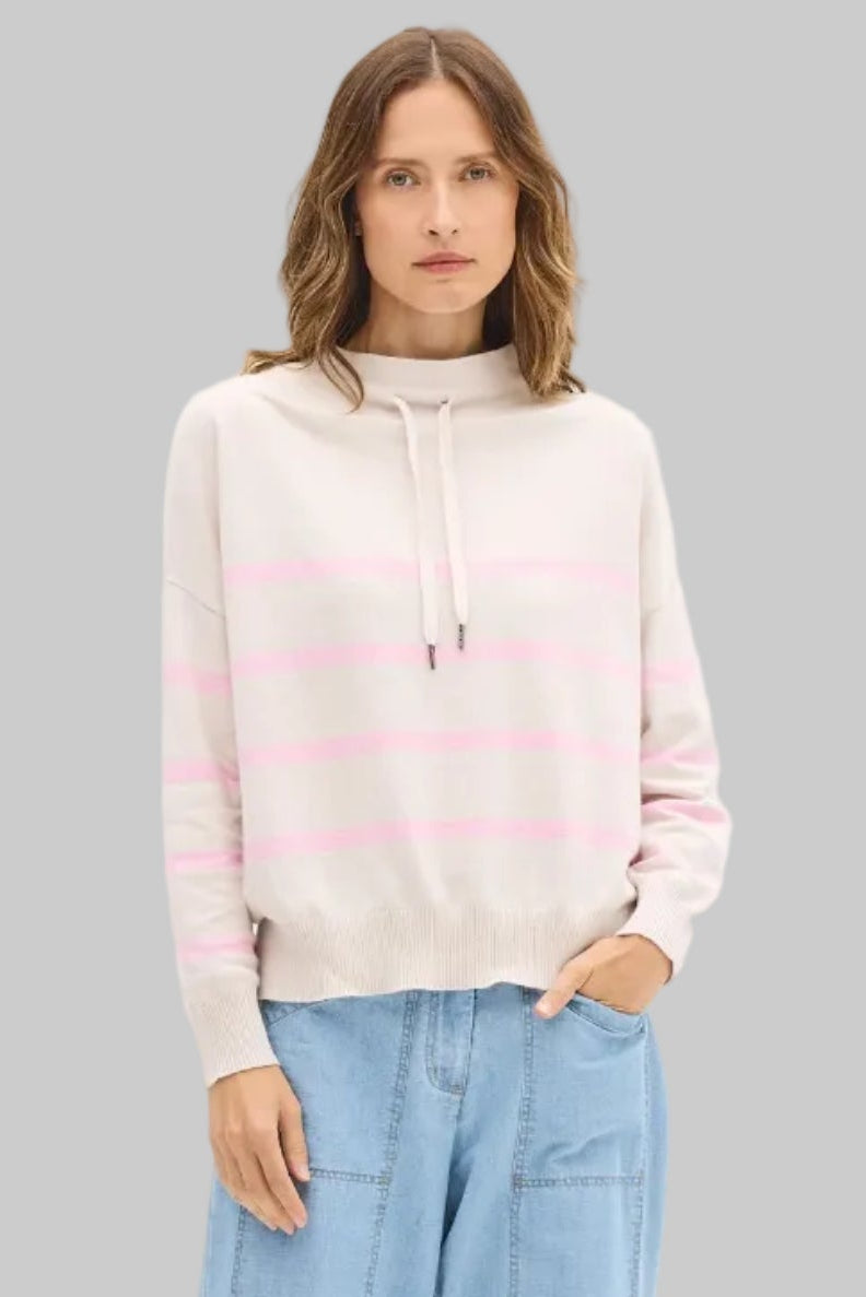 Woman wearing a striped sweater and light blue pants on a white background