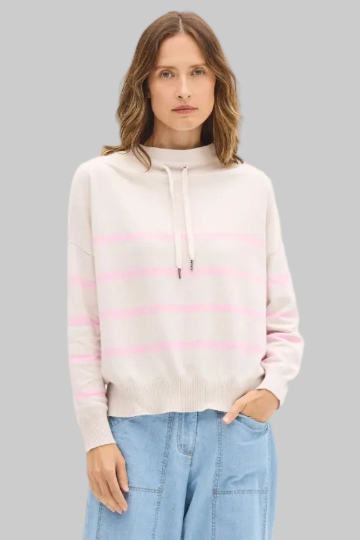 Woman wearing a striped sweater and light blue pants on a white background